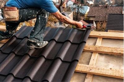 operario instalando tejas en techo casa