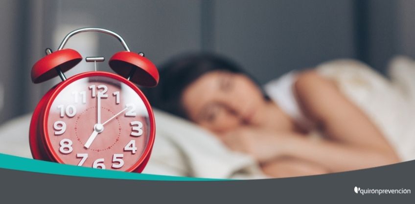 reloj despertador rojo y de fondo mujer durmiendo imagen grande
