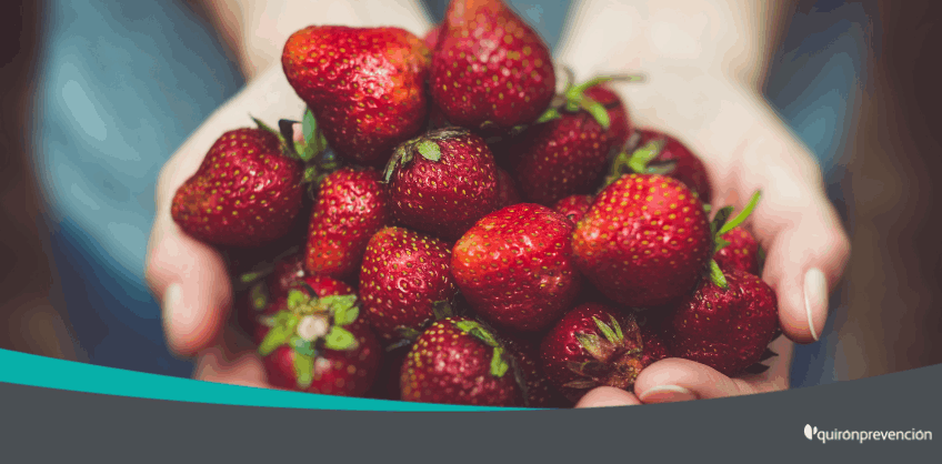 persona cogiendo con las manos un puñado de fresas imagen grande