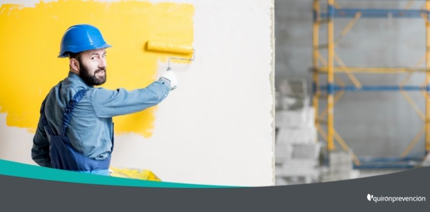 obrero con casco azul pintando pared amarilla imagen grande