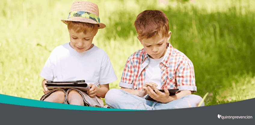 dos niños leyendo en el campo con una tableta imagen grande
