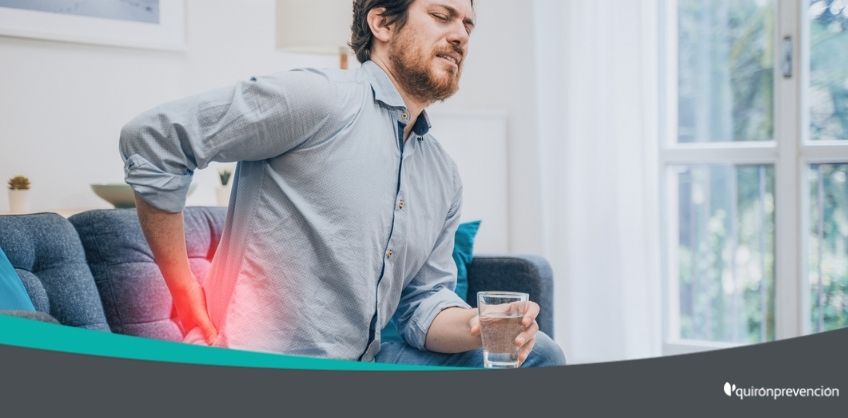 hombre sentado en sofá con dolor lumbar imagen grande